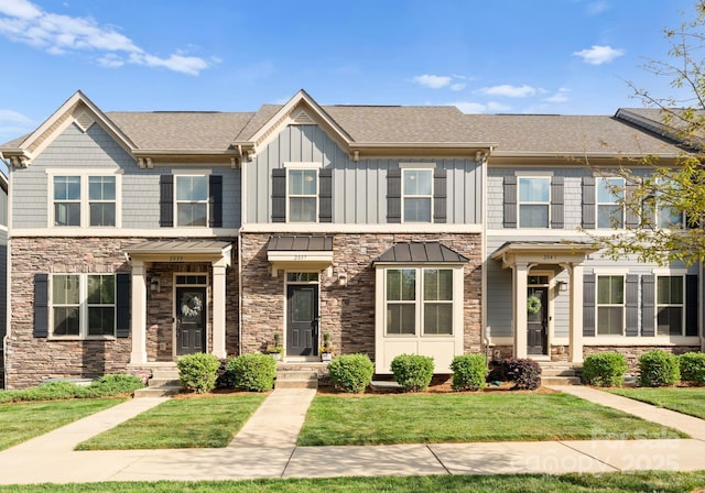 view of front of property featuring stone siding, a front lawn, and board and batten siding