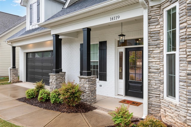 14119 Shelburne Village Dr, Charlotte, NC 28278 - entrance to property featuring covered porch, roof with shingles, concrete driveway, and stone siding