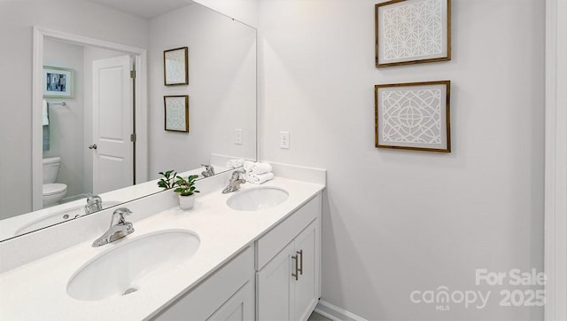 bathroom featuring double vanity, a sink, and toilet