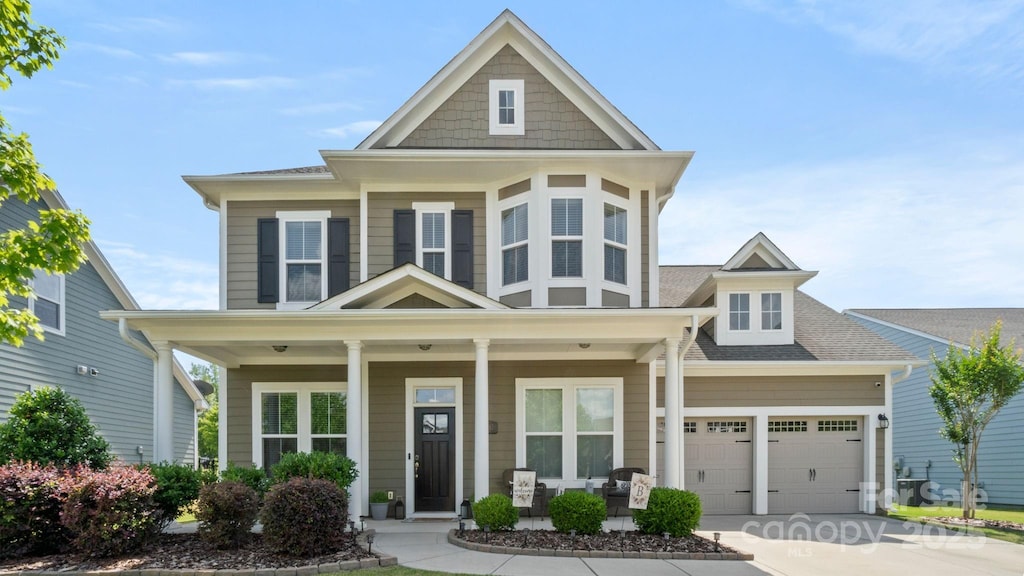view of front of home with a garage, covered porch, driveway, and roof with shingles