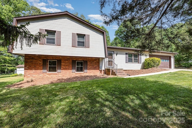split level home featuring a front lawn, an attached garage, and brick siding