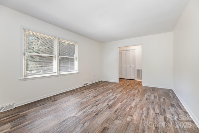 unfurnished room featuring visible vents, wood finished floors, and baseboards