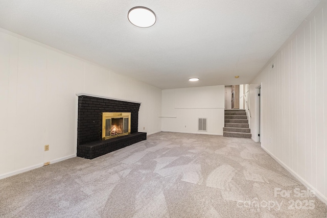 unfurnished living room featuring stairs, visible vents, carpet floors, and a fireplace