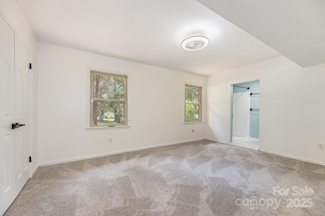 unfurnished bedroom with baseboards, carpet floors, and multiple windows