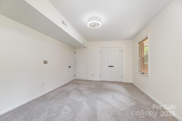 unfurnished room featuring visible vents, light carpet, and baseboards