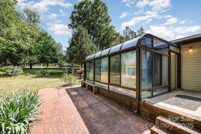 view of home's exterior featuring a lawn, a patio, and a sunroom