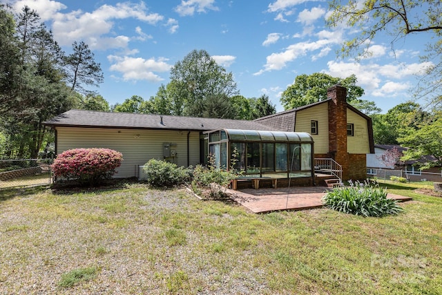 back of property with fence, a chimney, a patio, and a sunroom