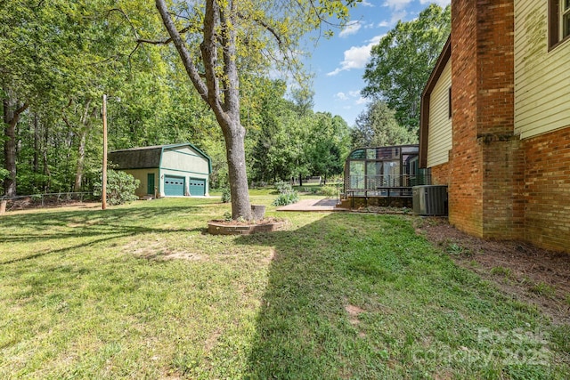 view of yard with fence, cooling unit, a detached garage, and an outdoor structure
