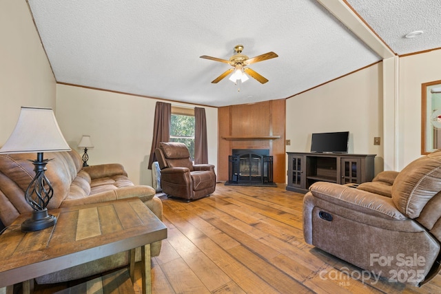 3317 Treyburn Dr, Midland, NC 28107 - living area with crown molding, light wood finished floors, a textured ceiling, a glass covered fireplace, and a ceiling fan