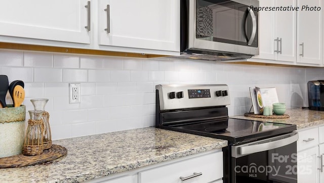 kitchen with white cabinets, backsplash, light stone countertops, and appliances with stainless steel finishes