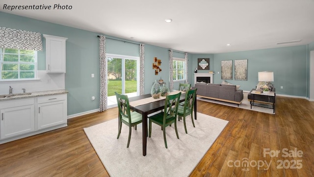 dining space featuring a fireplace, recessed lighting, baseboards, and dark wood-type flooring