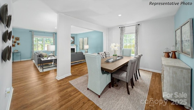 dining area featuring baseboards, recessed lighting, wood finished floors, and a fireplace