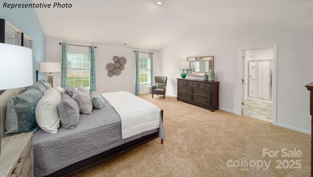 bedroom with ensuite bathroom, vaulted ceiling, carpet, and baseboards