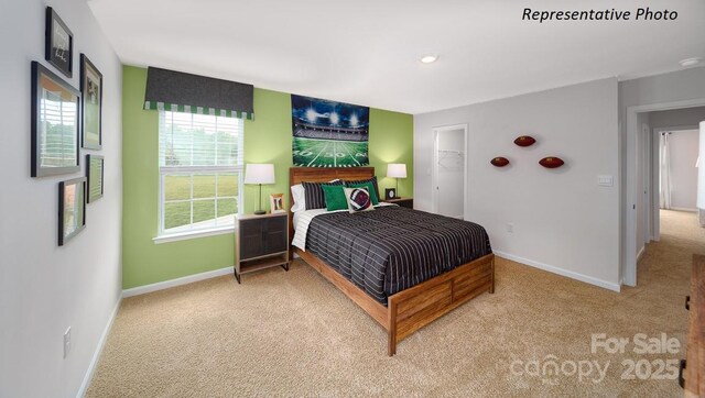 carpeted bedroom featuring a walk in closet and baseboards