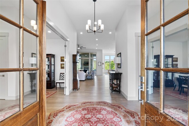 foyer entrance with light wood-type flooring, recessed lighting, and ceiling fan with notable chandelier