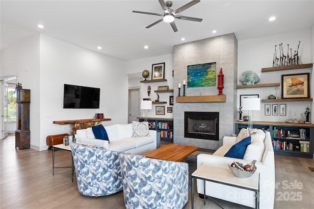 living area with wood finished floors, a fireplace, baseboards, recessed lighting, and a ceiling fan
