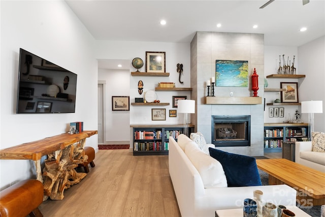 living area featuring recessed lighting, baseboards, wood finished floors, and a tile fireplace