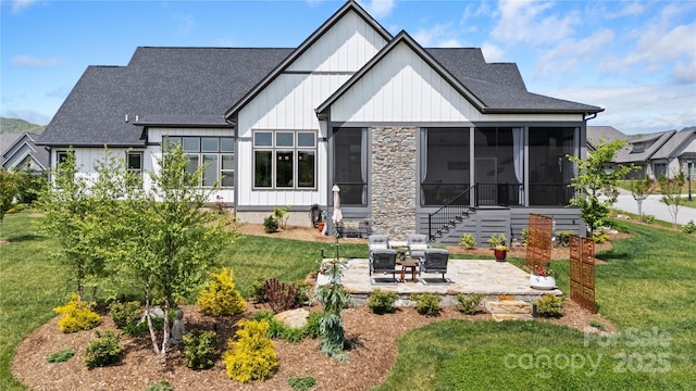 rear view of property featuring a lawn, a patio, a shingled roof, and a sunroom