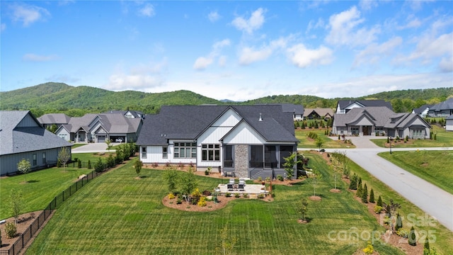 back of property featuring a sunroom, board and batten siding, a mountain view, and a residential view