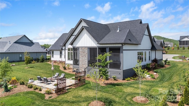exterior space with a yard, a patio, a shingled roof, and a sunroom