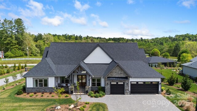 view of front of home featuring board and batten siding, a shingled roof, stone siding, and a garage