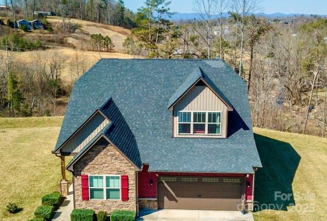 craftsman-style house featuring a front yard, stone siding, board and batten siding, concrete driveway, and an attached garage