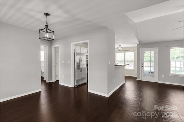unfurnished living room featuring dark wood-style flooring and baseboards