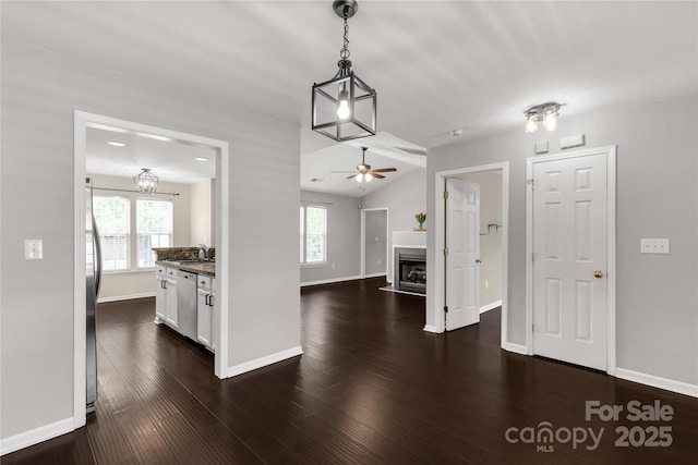 kitchen featuring stainless steel dishwasher, a sink, a fireplace, ceiling fan, and plenty of natural light