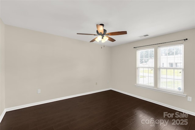 spare room with dark wood finished floors, visible vents, baseboards, and a ceiling fan