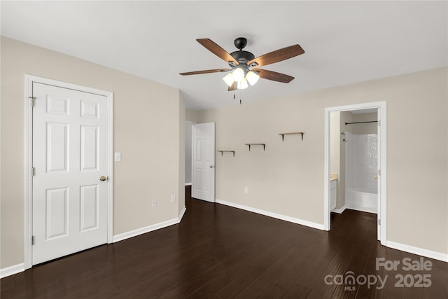 unfurnished bedroom featuring ensuite bath, wood finished floors, baseboards, and ceiling fan