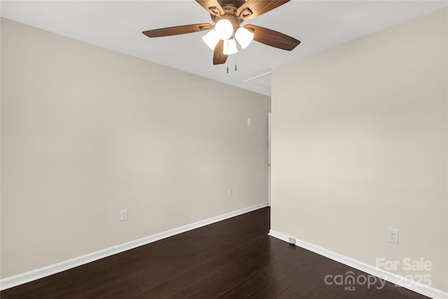 unfurnished room featuring attic access, baseboards, dark wood-style flooring, and a ceiling fan