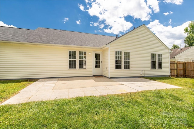 rear view of house featuring a patio area, roof with shingles, fence, and a lawn