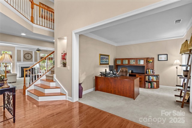 carpeted office featuring wood finished floors, a ceiling fan, crown molding, visible vents, and baseboards