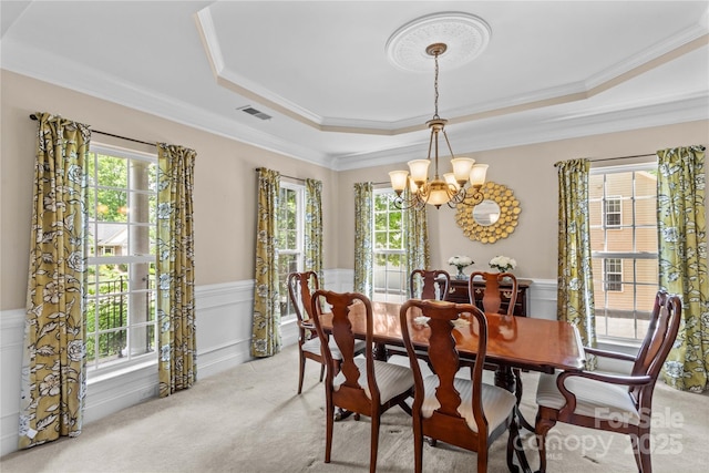 dining room featuring a tray ceiling, an inviting chandelier, plenty of natural light, and light carpet