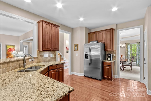 kitchen with a sink, recessed lighting, backsplash, stainless steel fridge, and light stone countertops