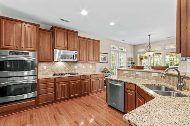 kitchen featuring decorative backsplash, stainless steel appliances, brown cabinetry, and a sink