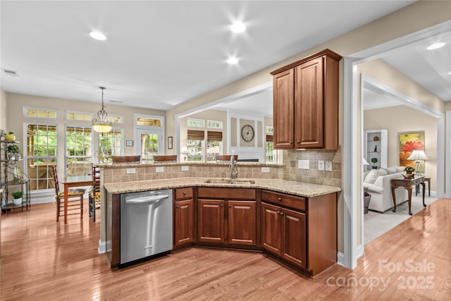 kitchen with a peninsula, light wood-style flooring, a sink, light stone countertops, and dishwasher