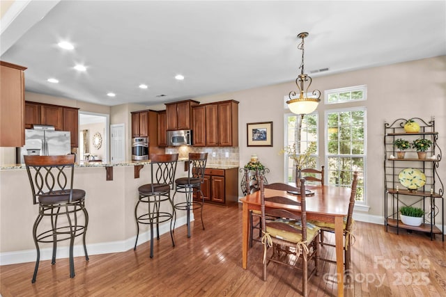 dining space with light wood-style flooring, baseboards, and recessed lighting