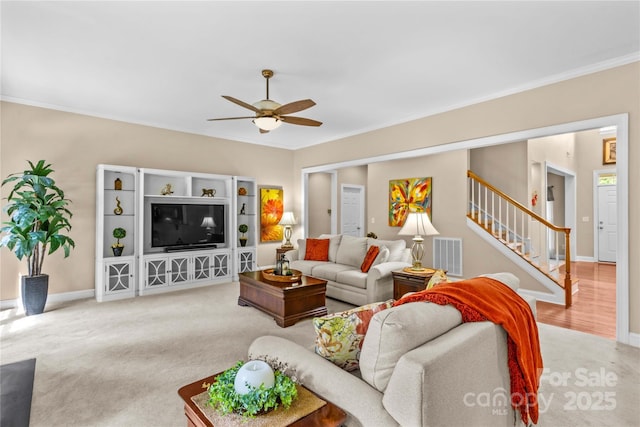 living area featuring ceiling fan, crown molding, visible vents, and stairway