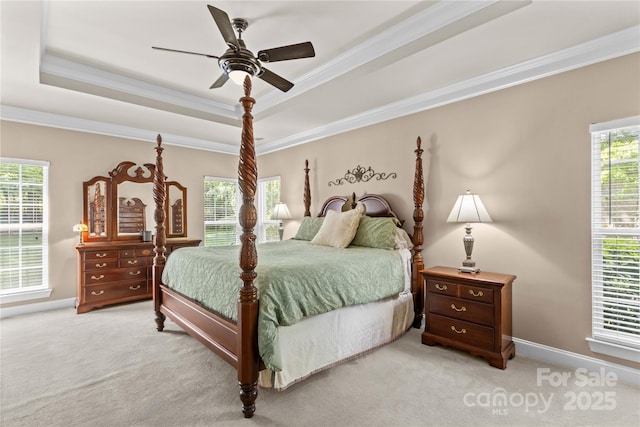 bedroom featuring a tray ceiling, crown molding, light carpet, and baseboards