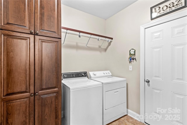 laundry room with cabinet space, washing machine and dryer, and baseboards