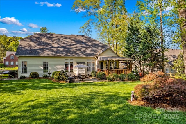 back of property with a lawn, a patio area, and a deck