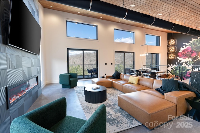 tiled living room featuring recessed lighting, baseboards, a towering ceiling, and a tile fireplace
