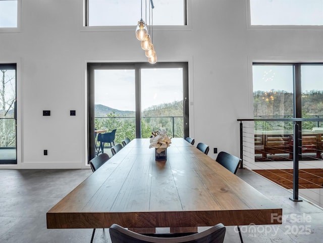 dining area with a healthy amount of sunlight, baseboards, finished concrete floors, and a towering ceiling