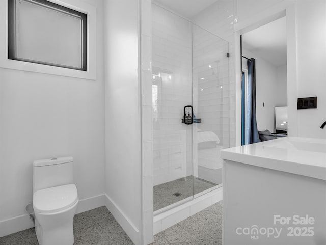 bathroom featuring vanity, toilet, speckled floor, baseboards, and a stall shower