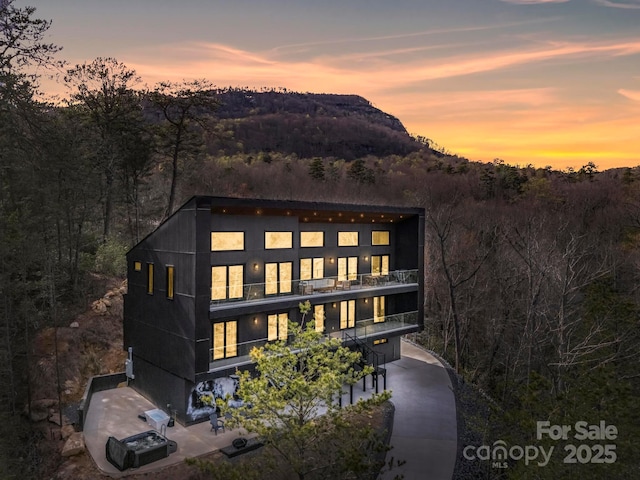 back of property featuring a view of trees and a balcony
