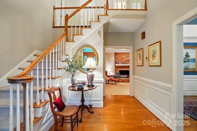 3804 Bellingham Ln, Charlotte, NC 28215 - entryway with a towering ceiling, wood finished floors, stairs, a brick fireplace, and wainscoting