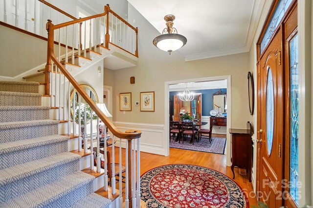 3804 Bellingham Ln, Charlotte, NC 28215 - entryway with light wood-style floors, stairs, a chandelier, ornamental molding, and wainscoting