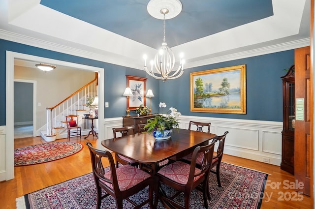 3804 Bellingham Ln, Charlotte, NC 28215 - dining area featuring a raised ceiling, stairs, wood finished floors, a chandelier, and a wainscoted wall