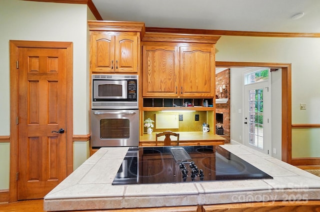 3804 Bellingham Ln, Charlotte, NC 28215 - kitchen featuring stainless steel appliances, tile countertops, crown molding, open shelves, and brown cabinets